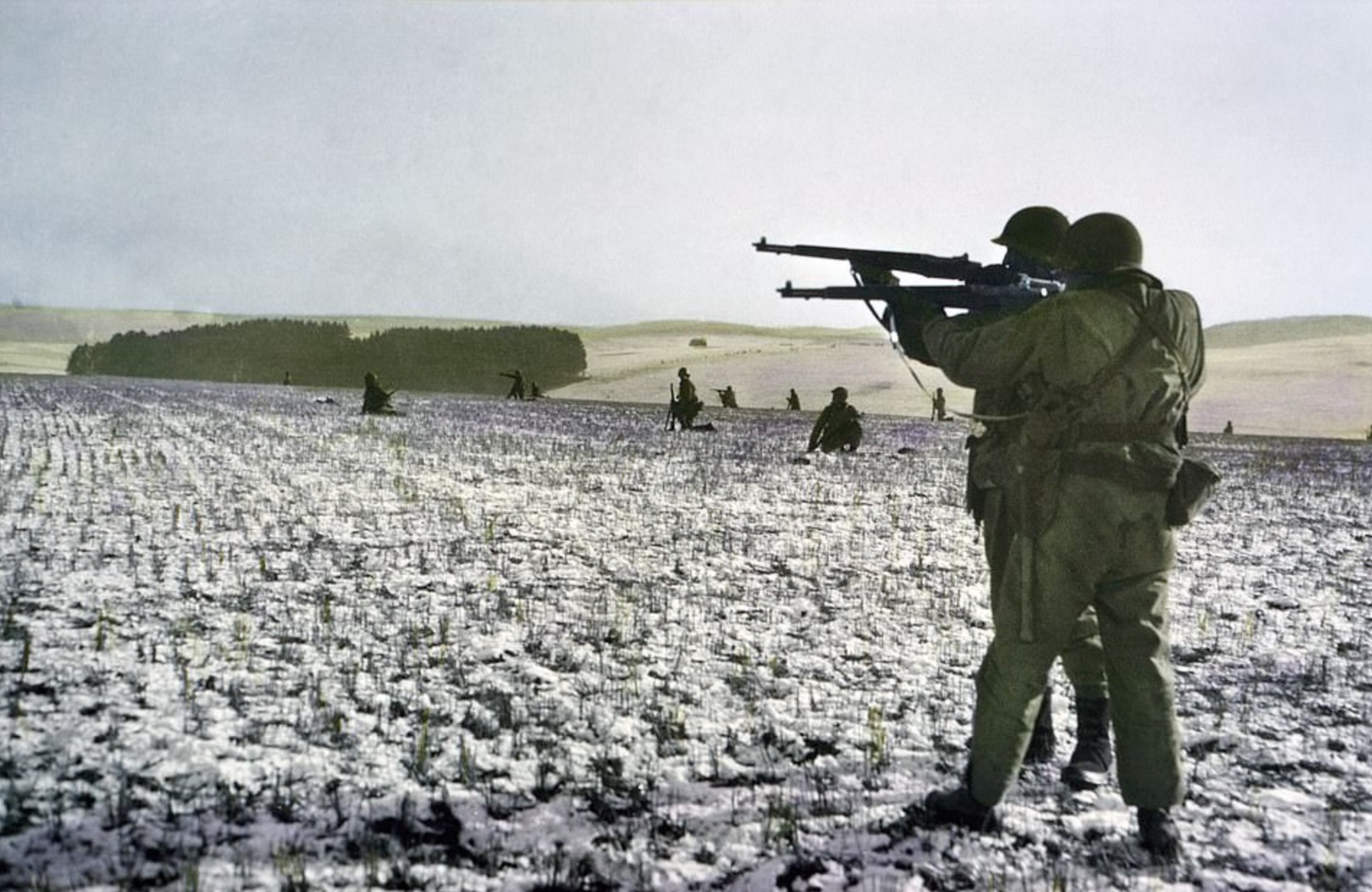 As they cross the field, two infantrymen fire at German troops across a field 